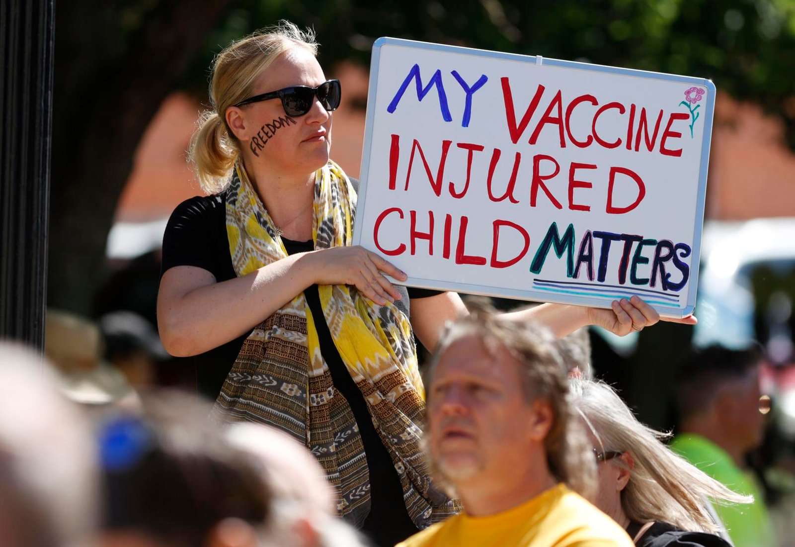 Simone Warstat of Louisville, Colo., waves a placard during a rally against a legislative bill to make it more difficult for parents to opt out for non-medical reasons to immunize their children Sunday, June 7, 2020, in Denver.